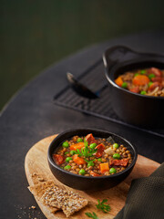 Lentil stew in bowl with vegetables, parsley chorizo spanish soup on a dark green background, copy space. Selective focus. Mediterranean healthy food concept.