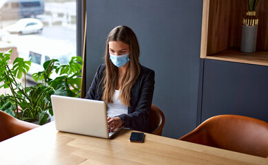 Businesswoman working on laptop wearing face masks protect from coronavirus in office