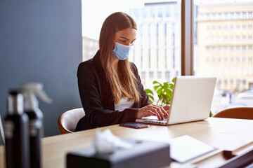 Businesswoman working on laptop wearing face masks protect from coronavirus in office