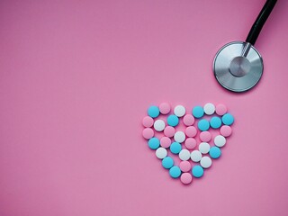 Heart shape of medicine pills and stethoscope on pink background. Concept of Valentine's Day or pharmacy, Medical. Health care