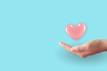 Close up of woman hands with heart with clean pastel background. Valentine's Day Love and care.