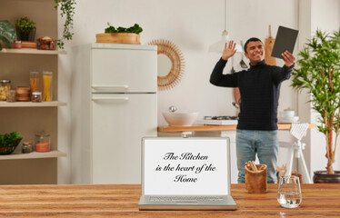Close up laptop screen on the wooden table, kitchen background with man using tablet and drink coffee.