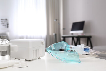 Modern nebulizer with face mask and medicines on white table indoors. Equipment for inhalation