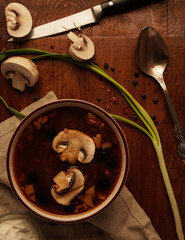 Flat-lay of mushroom soup with sour cream and onion on wooden table