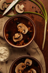 Flat-lay of mushroom soup with sour cream and onion on wooden table
