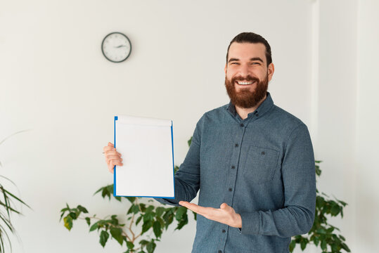 Photo of cheerful office worker man showing blank paper.