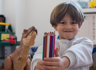 Child Showing A Set Of Colored Pencils To The Camera.