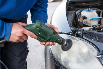 Male Worker Polishing The Headlight Of A Car.
General Worker Using Angle Grinder While Polishing Car Headlights In Workshop. Mechanic