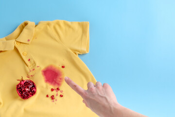 Finger pointing the dirty stain juice on yellow clothes. on a blue background. space for text
