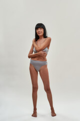 Always young and beautiful. Portrait of attractive half naked caucasian senior woman posing in lingerie against grey background