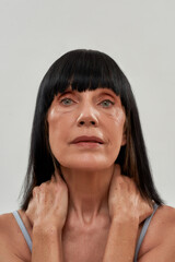 Healthy aging. Sensual half naked senior woman with natural beauty touching her neck and looking at...