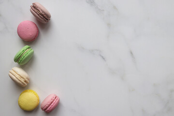 Frame made of French colorful macaroons pastries on a marble background with copy space. Top view, flat lay