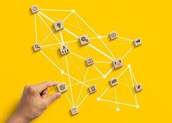 Business strategy to success, business management or start up business concept. Hand is arranging wooden blocks with business icon in low polygon rocket shape network on yellow background. - obrazy, fototapety, plakaty