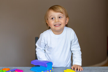 Cute caucasian blond  baby boy child playing with toy plasticine. Hand brain development activity for young toddler kids. Early age preschool education.