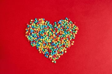 Heart made of multi-colored stars on red backgroud. Colorful valentines day