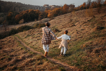 Cheerful pregnant mother spending time with her toddler son in autumnal  park. Mother and son. Family having fun outdoors 