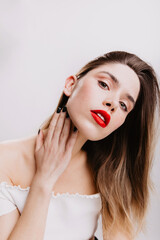 Obraz premium Attractive fashionable girl with red lipstick proudly looks into camera on white background