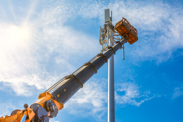 Crane with telescopic boom lift used as an aerial working platform. Worker install cellular base...