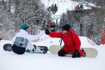 Fototapeta na wymiar Two snowboard riders sit on a slope