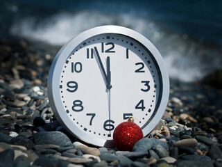 clock and Christmas ball on the beach at midnight