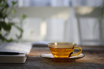 Tea in transparent glass cup on wooden table with notebook and pen