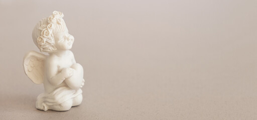 Banner, figurine of an angel Cupid with a bow on a pink background. Valentine's Day.