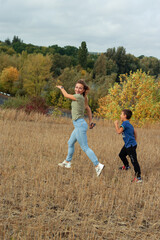 Mother and son are playing together outdoors in warm autumn day 