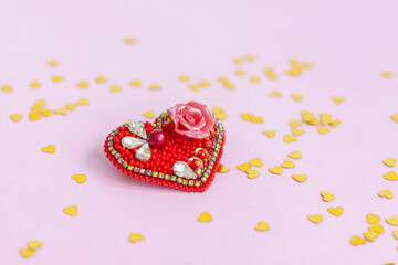Pink background with gold hearts, sequins. Red heart made of beads. The concept of the Valentine's Day theme. Postcard, template, background for graphic works. 