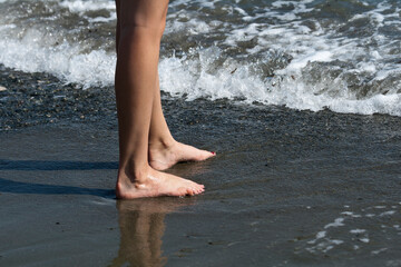 Woman's legs beside sea waves