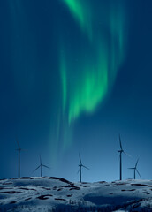 Wind turbines on a snowy hill at night with Aurora on the sky
