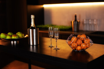 Kitchen interior with kitchen area with an island in loft style in dark colors. Champagne bottle in bucket with ice and glasses of Champagne on kitchen island. celebration concept. Valentine's day