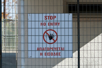 Bilingual no entry signboard on fence