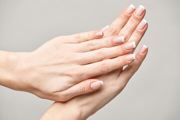 Beautiful Female Hands with French manicure over light grey background
