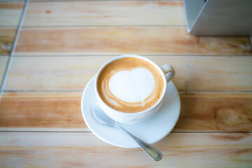 Hot latte art coffee on brown wood table