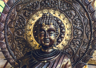 Closeup Thailand buddhism statue: bust Buddha monument with ornament circle background in temple. Religious asian sculpture with gold details. Oriental Thai interior sacred decoration close up shot