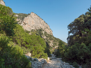 Fototapeta na wymiar A view of rocky hiking path to Cala Goloritze beach, limestone rocks. Famous travel destination. Gulf of Orosei, Sardinia, Italy, September