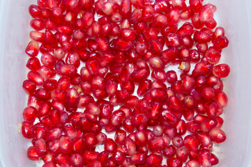 close-up on a pile of peeled pomegranate on white background. selective focus