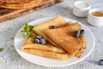 Thin pancakes for breakfast on a light concrete background.