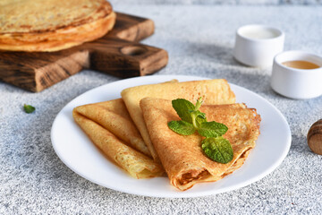 Thin pancakes for breakfast on a light concrete background.