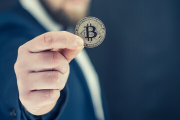 Virtual currency and blockchain concept. Businessman in a blue jacket holding Bitcoin in his hands.