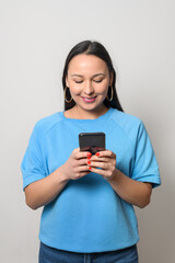 Young woman using smartphone and smiling on a white background.
