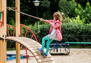 Little girl climbing rope on playground