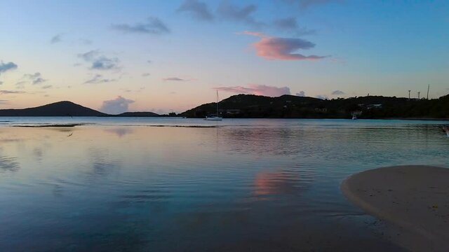 This is a High Definition video, 29.97 fps, of Datiles Beach in Culebra, Puerto Rico featuring an orange sunset over calm waters with sea birds and boats in the background