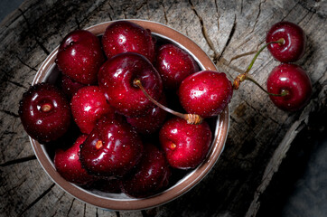 Fresh, clean cherries in a bowl on a wooden board. Photo in a rustic style for illustration on a...