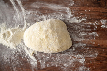 Ball of pizza dough on a rustic wooden background with dusting of flour