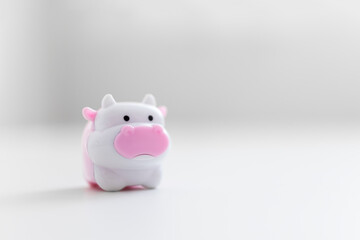 pink and white plastic toy cow on a light festive background