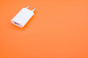 High angle shot of a white adaptor on an orange surface