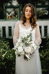 lovely young bride walks with a bouquet of flowers along the footpath in the botanical garden. floristry of a wedding bouquet. festive white flowers. Wedding Dress. beautiful modern dress.