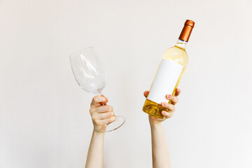 Human hands holding a wine glass and bottle of white wine on wall background. - Powered by Adobe