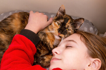 teenage girl in red pajamas sleeping on a pillow with a domestic cat